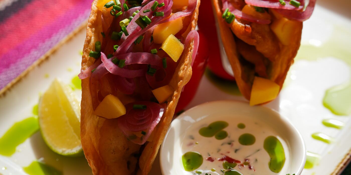 Taco De Pescado z mango i marynowaną cebulą, obok sos i limonka